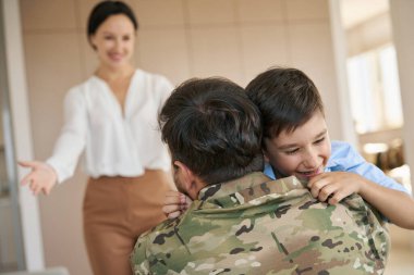Soldier returned home to his sweet wife and happy teenage son, the boy hugs his father tightly