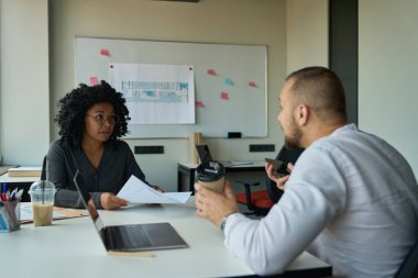 Colleagues in the office, multiracia woman and bearded man are discussing working moments