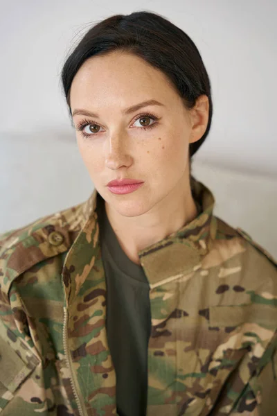 Portrait of a charming dark-haired young woman in military uniform, she has regular features, expressive big eyes
