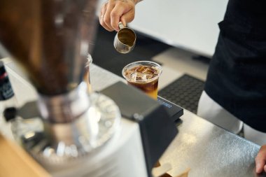 Cropped photo of virtuoso barista preparing to pour a shot of espresso into an iced coffee drink