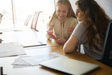 Neşeli bayan cihazın içeriğini iş yerinde çalışan bir meslektaşına gösteriyor.