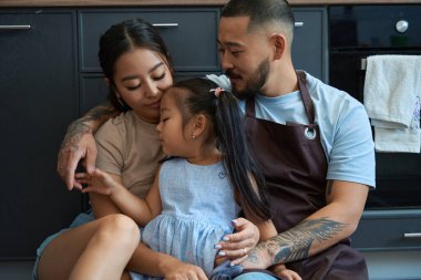 Ailesinin kollarında uyuyakalmış iki kuyruklu küçük kız uykusunu koruyor.