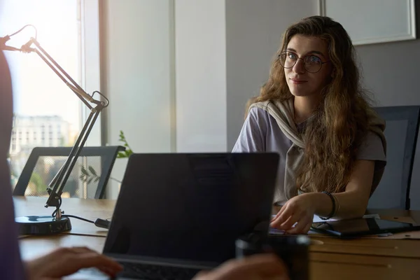 Interessante Junge Frau Mit Brille Blickt Geradeaus Während Kollegin Vor — Stockfoto