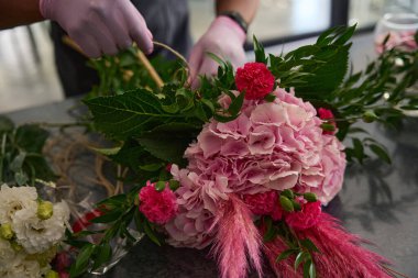 Masadaki erkek eller çiçekçide bir buket çiçek istifledi.