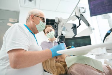 Dişleri doldurmak için mikroskop ve ekipman kullanan profesyonel bir dişçi. Stomatoloji kavramı