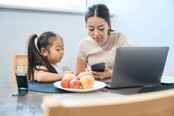 Mutter Zeigt Ihrer Kleinen Tochter Telefon Etwas Davor Liegt Laptop — Stockfoto