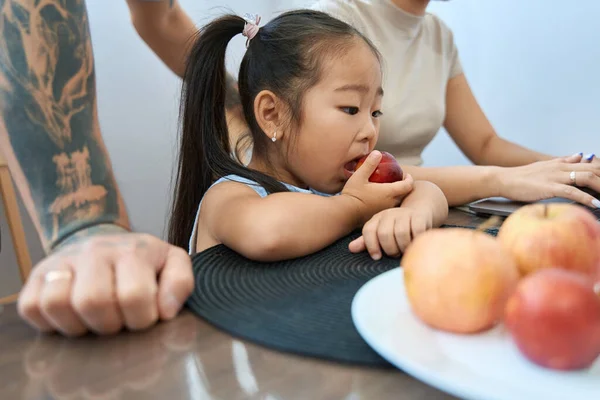 Asian Girl Ponytails Sits Table Eats Peach Supervision Her Parents — Stock Photo, Image