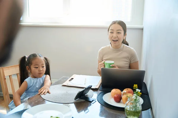 Frau Und Asiatisches Mädchen Küchentisch Mit Laptop Und Telefon Auf — Stockfoto