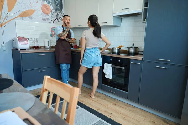 Man and a woman are having fun talking about something in the kitchen, the kitchen is equipped with modern gadgets