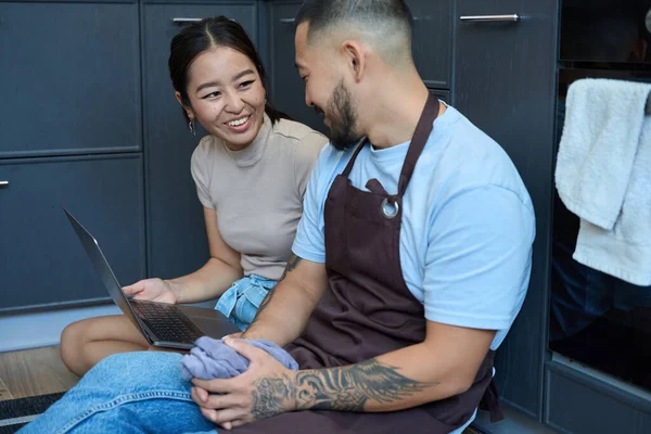 Genç Asyalı Çift Neşeli Kadın Önlüklü Adam Mutfak Zemininde Dizüstü — Stok fotoğraf