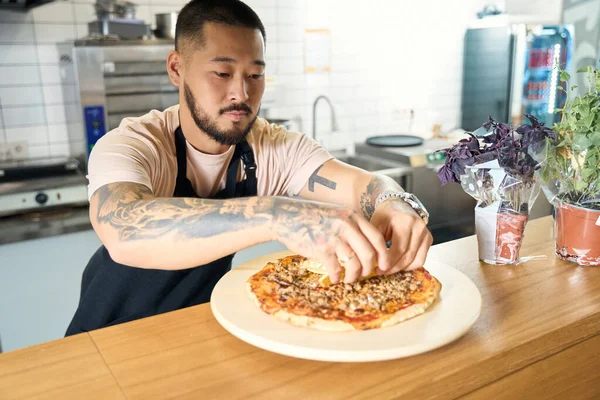 Jovem Concentrado Avental Temperando Uma Pizza Recém Cozida Cozinha — Fotografia de Stock