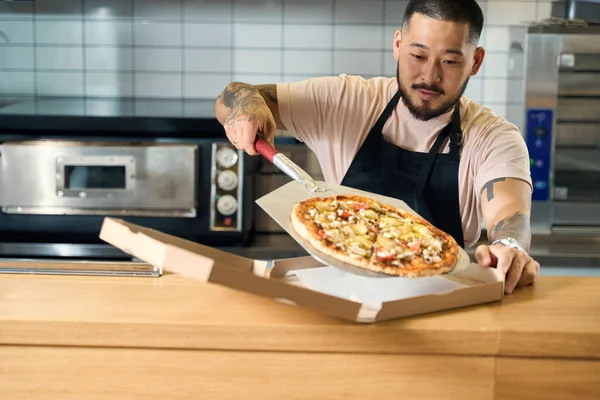 Homem Puro Avental Cozinha Colocando Cuidadosamente Uma Pizza Fresca Uma — Fotografia de Stock