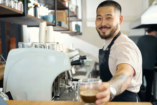 Guapo Joven Camarero Sonriendo Cámara Mientras Ofrece Una Taza Café — Foto de Stock