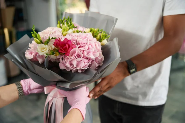 Male buyer picks up a bouquet of flowers from the seller