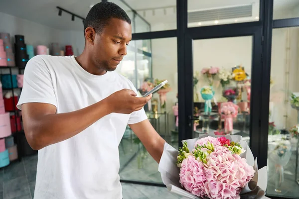 In a flower shop, a man shoots a flower bouquet on camera