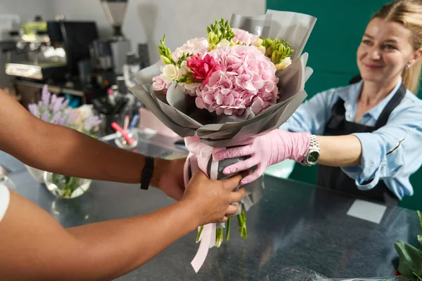 Seller gives a flower bouquet to the man behind the counter