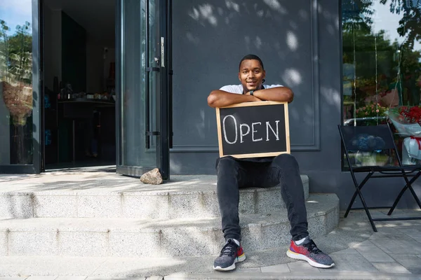 Afroamericano Sienta Cerca Tienda Con Letrero Sus Manos —  Fotos de Stock