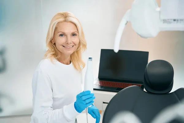 Πορτρέτο Του Χαμογελαστού Οδοντίατρου Κρατώντας Συσκευή Για Σάρωση Και Κάθεται — Φωτογραφία Αρχείου