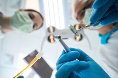 Makine ve diş aynası kullanarak dişi dolduran dişçinin alt görünümü