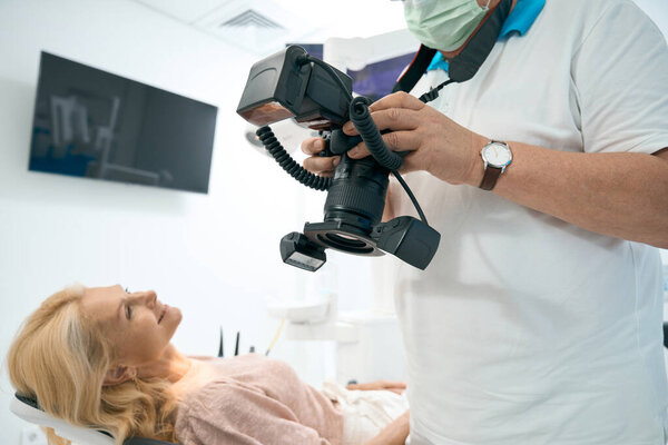 Врач просматривает фото зубов пациентки на камеру