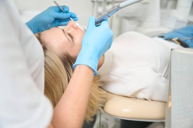 Eldivenli doktor diş temizliği için gerekli aletleri elinde tutuyor.