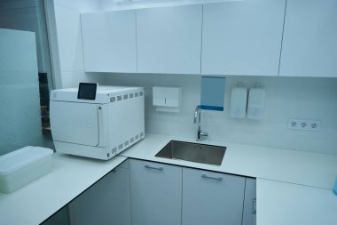 Dolapları, lavabosu ve sterilizasyon aletleri olan dişçi ofisi. Modern dişçilik