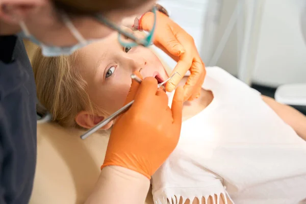 Childrens doctor in gloves and glasses treats a childs teeth