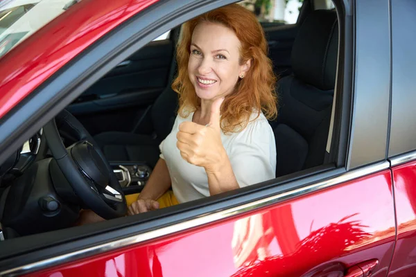Satisfied Smiling Red Haired Woman Sits Wheel Red Car Shows — Stock Photo, Image
