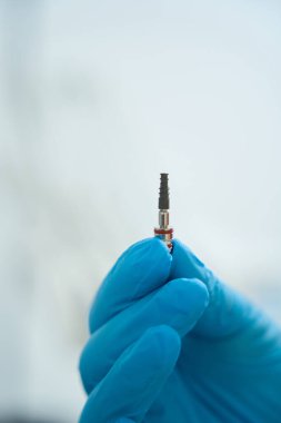 Mavi tıbbi eldivenli dişçi diş yenileme için pimi tutuyor. Diş hekimi için tüketiciler