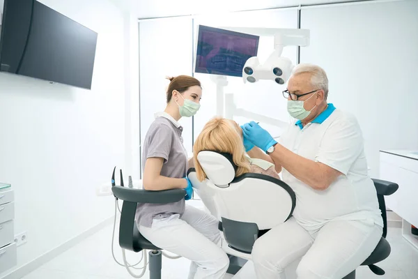 ハンサムな白人の歯医者の完全な長さの肖像画は歯科事務所でプロの歯のクリーニングを作っている — ストック写真