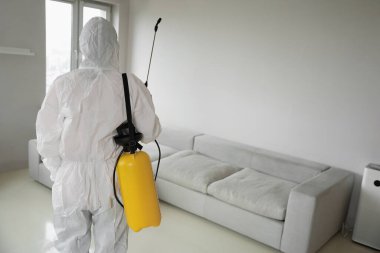 Beyaz üniformalı temizlik şirketinin sarı spreyli dezenfektanı.