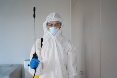 Beyaz üniformalı bir kadın ve dezenfekte için solunum cihazı tutuyor.