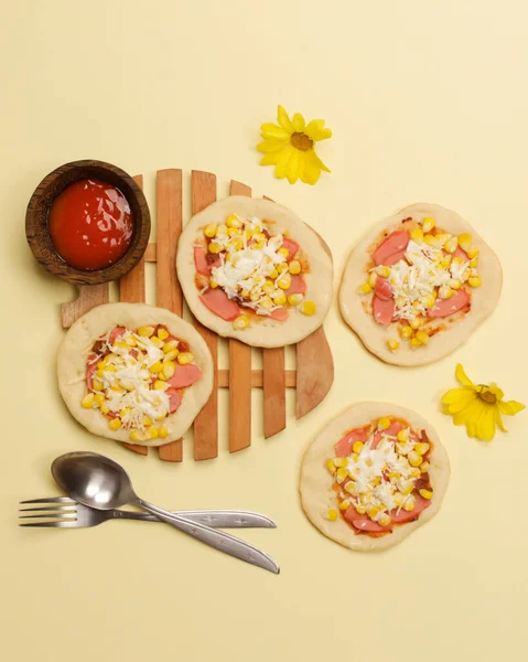 Mini pizza with corn, sausage and cheese topping for your lunch menu. pizza is a savory dish from Italy a kind of round and flat dough, baked in the oven. Pizza mockups. Focus blur. Focus on some angels.