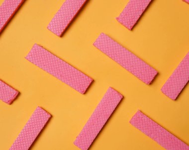 Sarı arka planda düzgünce yerleştirilmiş pembe gofret yığınları. Bir yığın taro aromalı gofret. Lezzetli ve gevrek atıştırmalıklar. Atıştırmalık Renkli gofretler. Yemek fotoğrafçılığı. Lezzetli