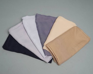 Gri arkaplana düzgünce yerleştirilmiş çıplak renkli peçeler. Müslüman kadınlar için kullanılmaya hazır gri renkli ince kumaş karışımı. Satış gösterileri için de kullanılabilir. Odak bulanıklığı. tesettür.