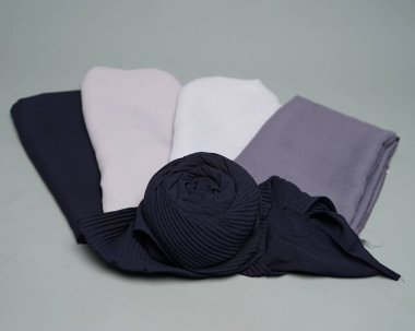 Çıplak gri kumaşların karışımı düzgünce düzenlenmiş. Çiçek yapraklarına benzemek için sarılmış, Müslüman kadınlar için kullanılmaya hazır. Bayramdan önce Ramazan ayında moda gereksinimleri. Odak bulanıklığı. Başörtüsünü düzelt.