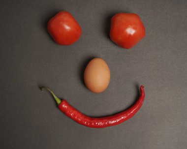 The combination of fresh tomatoes, red chilies and eggs forms a smiling face. Cooking ingredients ready to be served. focus blur, background inspiration. black and red color combination.