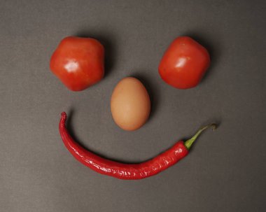 The combination of fresh tomatoes, red chilies and eggs forms a smiling face. Cooking ingredients ready to be served. focus blur, background inspiration. black and red color combination.