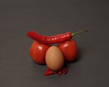 The combination of fresh tomatoes, red chilies and eggs forms a smiling face. Cooking ingredients ready to be served. focus blur, background inspiration. black and red color combination.