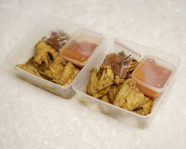 Chicken wrapped with Indonesian spices. Chicken pieces are ready to be fried. Ready-to-eat food in box packaging complete with chili sauce etc. Food packaging mockup box for template. Focus blur.