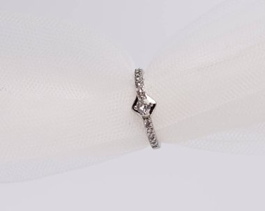 Mücevher yüzüğünün kumaş rulosuna yerleştirilmiş konsept fotoğrafı. Derin bir anlamı ve anlamı olan alyanslar. Mücevher ya da elmaslı nişan yüzüğü. Alyans beyaz arkaplanda izole edildi.