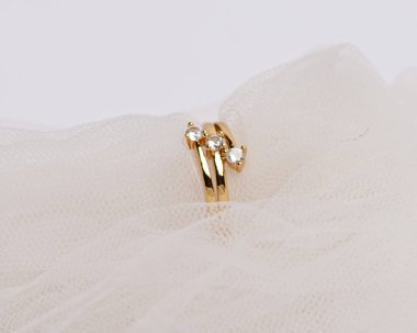 Mücevher yüzüğünün kumaş rulosuna yerleştirilmiş konsept fotoğrafı. Derin bir anlamı ve anlamı olan alyanslar. Mücevher ya da elmaslı nişan yüzüğü. Alyans beyaz arkaplanda izole edildi.