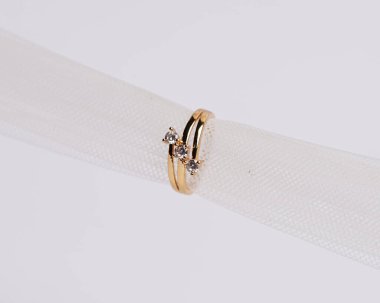 Mücevher yüzüğünün kumaş rulosuna yerleştirilmiş konsept fotoğrafı. Derin bir anlamı ve anlamı olan alyanslar. Mücevher ya da elmaslı nişan yüzüğü. Alyans beyaz arkaplanda izole edildi.