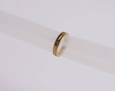 Mücevher yüzüğünün kumaş rulosuna yerleştirilmiş konsept fotoğrafı. Derin bir anlamı ve anlamı olan alyanslar. Mücevher ya da elmaslı nişan yüzüğü. Alyans beyaz arkaplanda izole edildi.