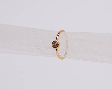 Mücevher yüzüğünün kumaş rulosuna yerleştirilmiş konsept fotoğrafı. Derin bir anlamı ve anlamı olan alyanslar. Mücevher ya da elmaslı nişan yüzüğü. Alyans beyaz arkaplanda izole edildi.