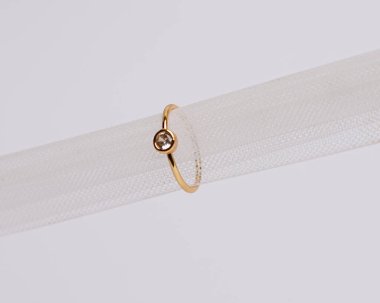 Mücevher yüzüğünün kumaş rulosuna yerleştirilmiş konsept fotoğrafı. Derin bir anlamı ve anlamı olan alyanslar. Mücevher ya da elmaslı nişan yüzüğü. Alyans beyaz arkaplanda izole edildi.