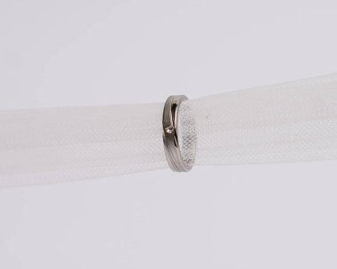 Mücevher yüzüğünün kumaş rulosuna yerleştirilmiş konsept fotoğrafı. Derin bir anlamı ve anlamı olan alyanslar. Mücevher ya da elmaslı nişan yüzüğü. Alyans beyaz arkaplanda izole edildi.