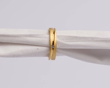 Mücevher yüzüğünün kumaş rulosuna yerleştirilmiş konsept fotoğrafı. Derin bir anlamı ve anlamı olan alyanslar. Mücevher ya da elmaslı nişan yüzüğü. Alyans beyaz arkaplanda izole edildi.