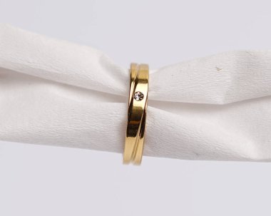 Mücevher yüzüğünün kumaş rulosuna yerleştirilmiş konsept fotoğrafı. Derin bir anlamı ve anlamı olan alyanslar. Mücevher ya da elmaslı nişan yüzüğü. Alyans beyaz arkaplanda izole edildi.