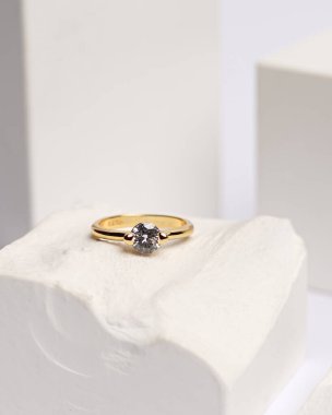 Alyans beyaz taşa takılmış. Mücevher yüzüğü sergilenip satılmaya hazır. Alyans, bu çiftin aşkının bir işareti. İnciler ve elmaslar yüzüğün güzelliğini tamamlıyor. odak bulanıklığı.